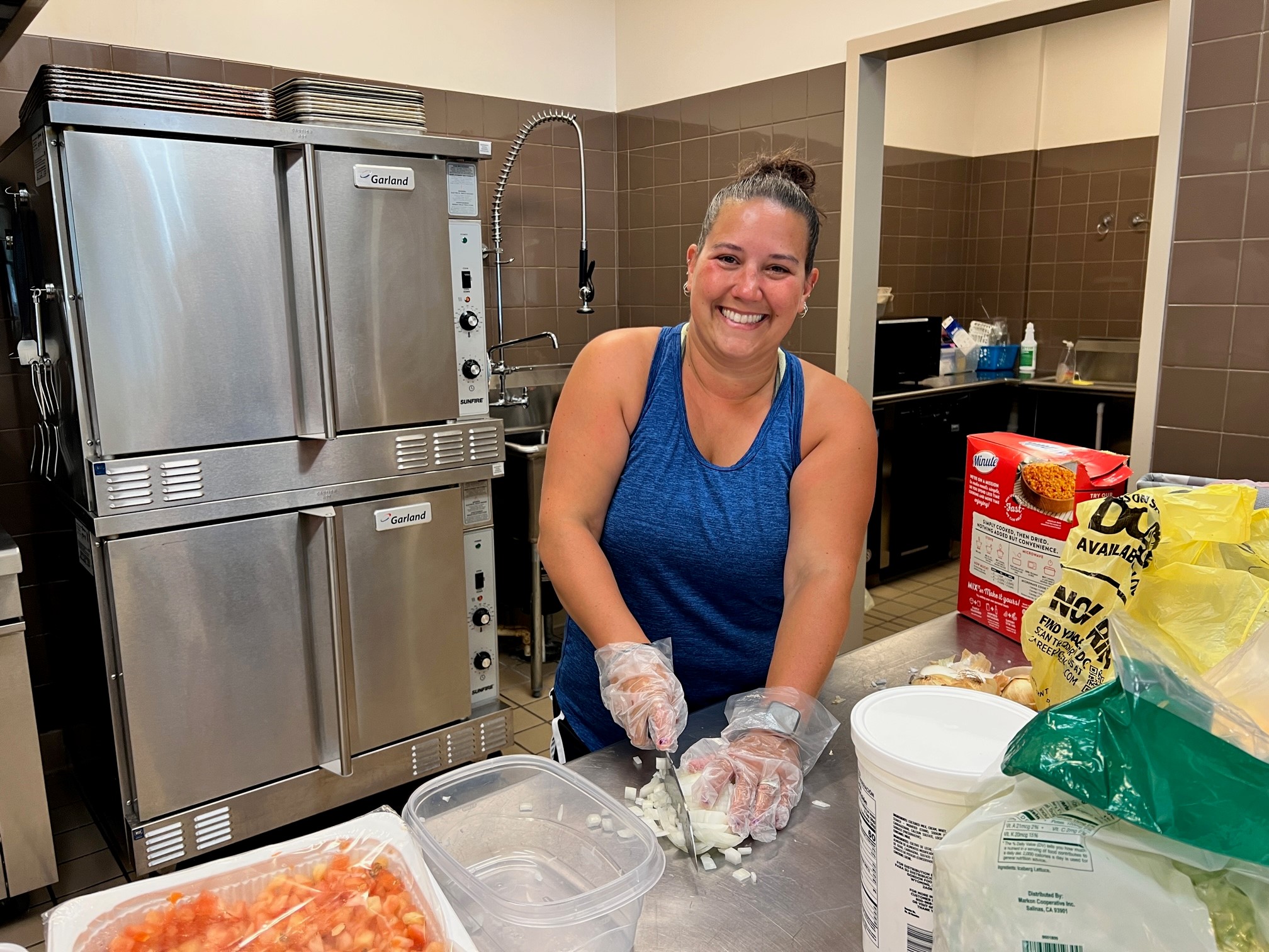 Michelle Wax cutting onions for toppings at their taco bar.